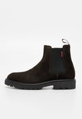 Brauner Chelsea-Stiefel aus Wildleder mit schwarzem elastischem Seitenpanel, Zuglasche und einer klobigen schwarzen Gummisohle. Glatte Textur und klares Design.