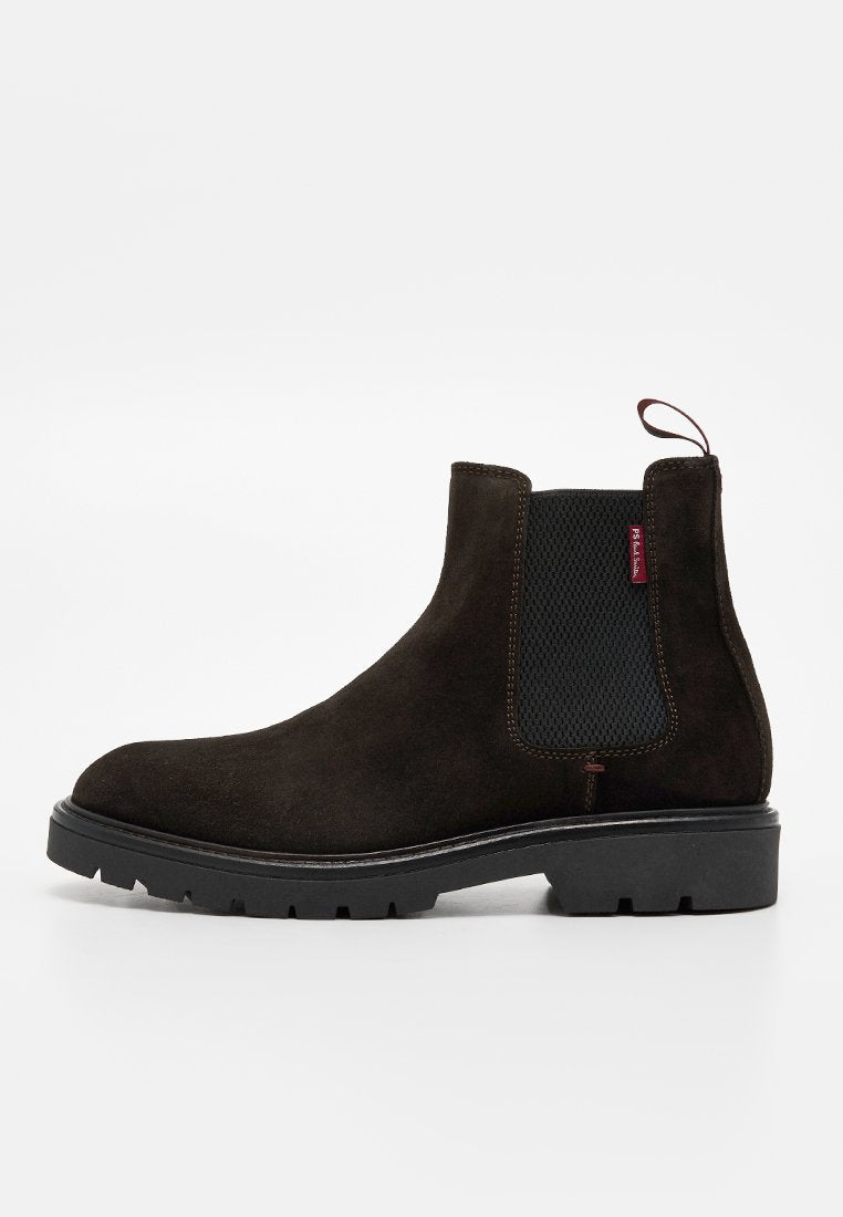 Brauner Chelsea-Stiefel aus Wildleder mit schwarzem elastischem Seitenpanel, Zuglasche und einer klobigen schwarzen Gummisohle. Glatte Textur und klares Design.