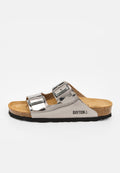 Silberne Slip-On-Sandale mit zwei verstellbaren Schnallenriemen, Kork-Fußbett, schwarzer Sohle und "BAYTON" Logo an der Seite.