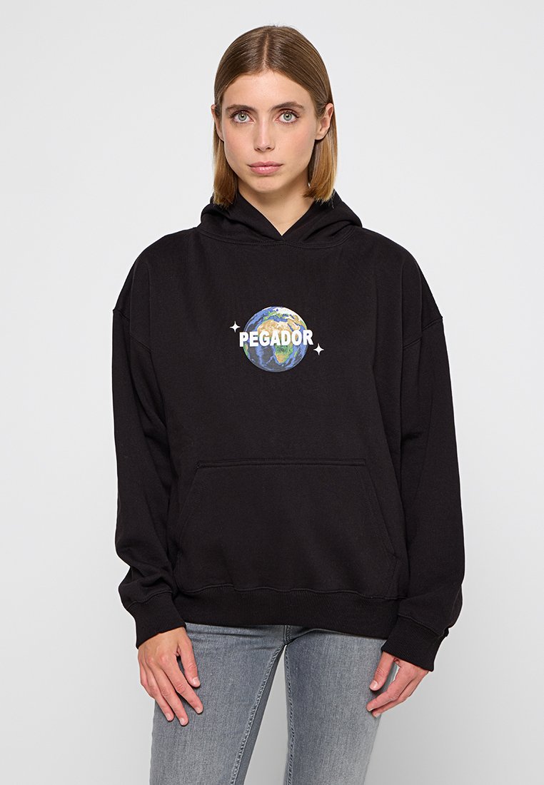 Schwarzer oversize Kapuzenpulli mit einer Fronttasche, versehen mit einem runden Grafikdesign der Erde und dem Text "PEGADOR." Hergestellt aus weichem Stoff.