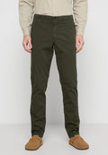 Olivgrüne Chinos mit geradem Schnitt, aus einem Baumwollgemisch, mit Knopfverschluss und Gürtelschlaufen, kombiniert mit braunen Wildleder-Schlupfschuhen.