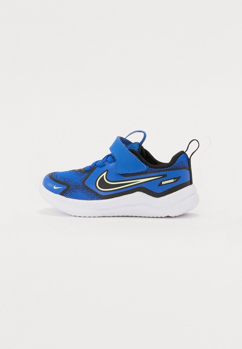 Blaue Sport Schuhe mit einem Obermaterial aus Netzgewebe, schwarzen Akzenten, einer weißen Sohle und einem Klettverschluss. Merkmale ein auffälliges Nike-Logo in Gelb.