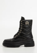 Schwarze Leder-Stiefelette mit gestepptem Muster, goldenen Ösen, runder Zehenpartie, dicker Plateausohle und dekorativem Metallelement an der Seite.