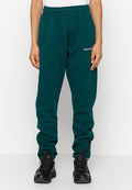 Grüne Fleece-Sweatpants mit elastischem Bund, seitlichen Taschen und einem weißen Logo auf dem linken Oberschenkel. Kombiniert mit schwarzen Sportschuhen.