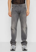 Frontalansicht einer Person in ausgewaschenen grauen Jeans, weißen und grauen Turnschuhen sowie einem schwarzen Netzoberteil, die vor einem weißen Hintergrund steht.