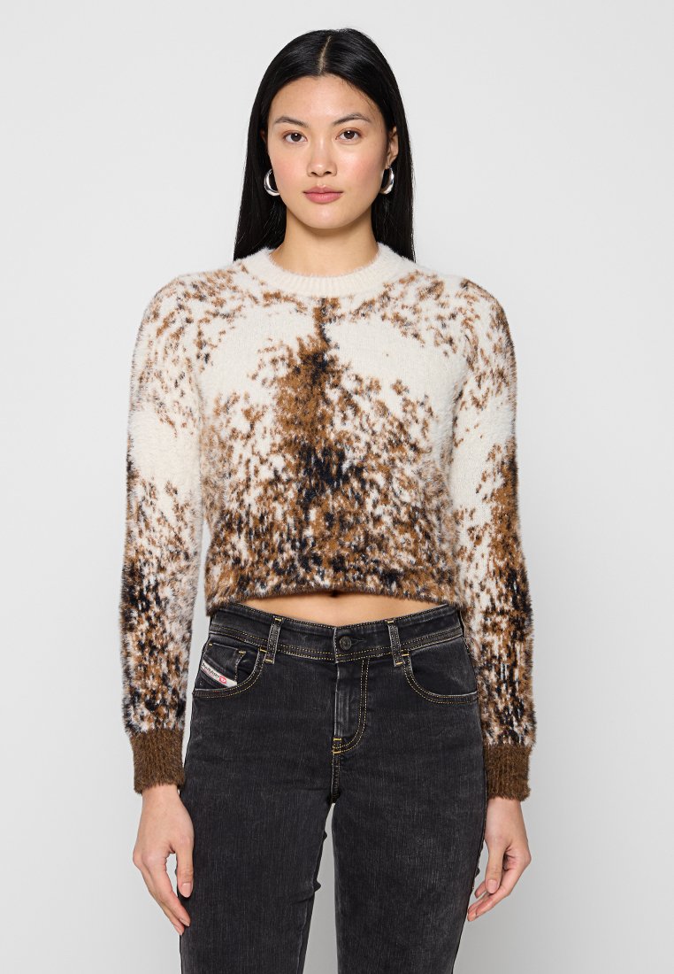 Braun- und cremefarbener gemusterter Strickpullover, verkürzte Silhouette, weiche Textur, runder Halsausschnitt, lange Ärmel mit gerippten Bündchen, kombiniert mit dunklen Jeans.
