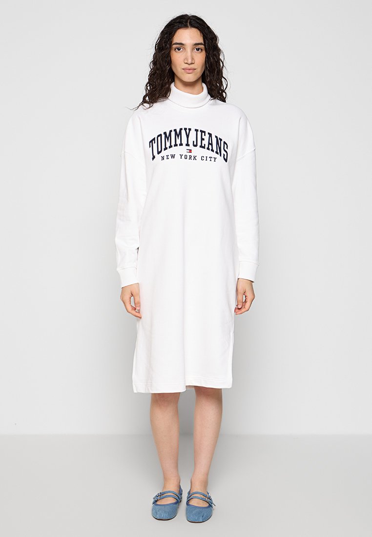 Weißes Sweatshirtkleid mit langen Ärmeln, ausgestattet mit einem dunkelblauen "TOMMY JEANS NEW YORK CITY" Logo. Flacher Halsausschnitt und knielange Passform.