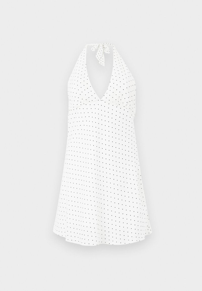 Weißes Halterkleid mit tiefem V-Ausschnitt, mit gebundenem Hals und schwarzen Polka-Dots. Fließender Stoff mit leicht geschwungenem Saum.