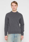 Grauer Pullover mit rundem, mehrfarbig geripptem Kragen und langen Ärmeln, gefertigt aus weichem Material. Über hellblauen Jeans getragen.