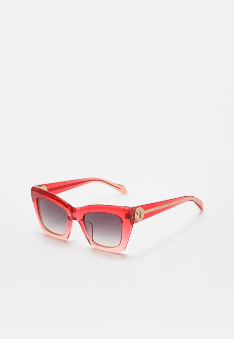 Rote Verlaufs-Sonnenbrille mit quadratischem Rahmen, goldenen Details und einem runden Logo-Emblem an den Bügeln, abgebildet vor weißem Hintergrund.