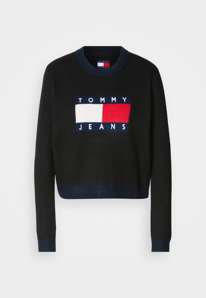 Schwarzer Pullover mit langen Ärmeln und Rundhalsausschnitt, ausgestattet mit einem blauen, weißen und roten Logopatch, auf dem "TOMMY JEANS" auf der Vorderseite steht.