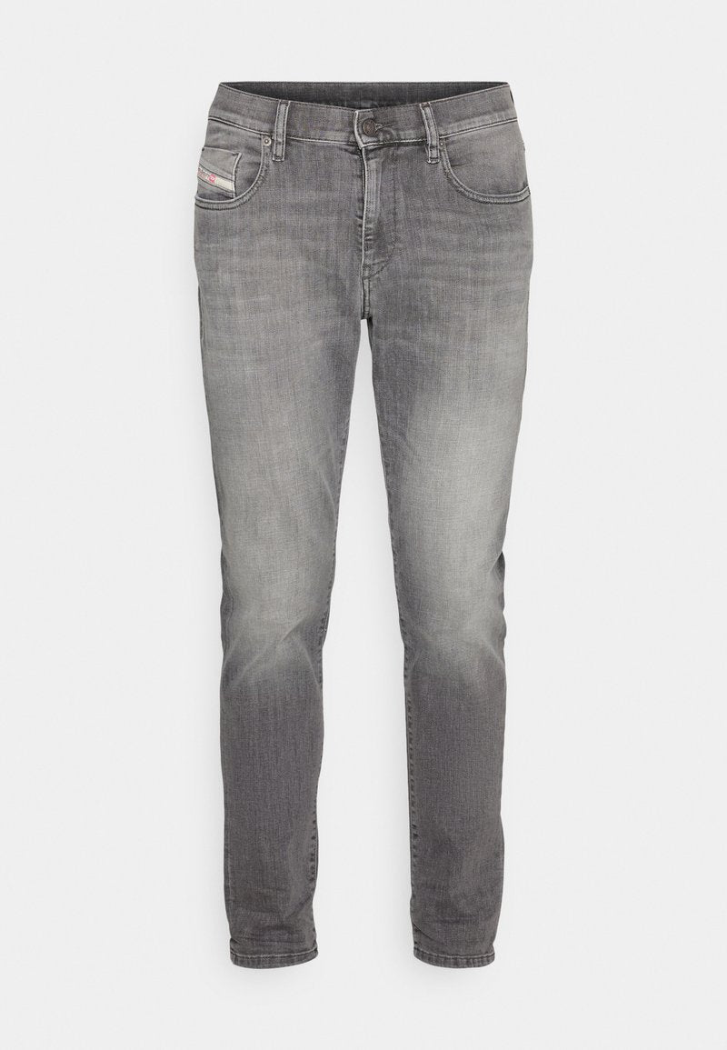 Graue Denim-Jeans im Slim-Fit, mit ausgebleichten Bereichen für Textur, Fünf-Taschen-Design und einem kleinen Logo-Patch auf der vorderen Tasche.