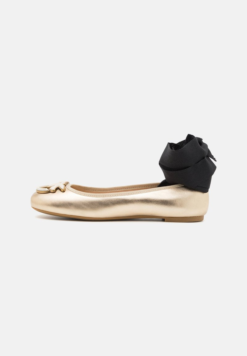 Goldfarbene metallische Ballettschuhe mit runder Spitze, ausgestattet mit einem dekorativen Blumenakzent und einem schwarzen Stoffknöchelriemen mit einer Schleifendetail.