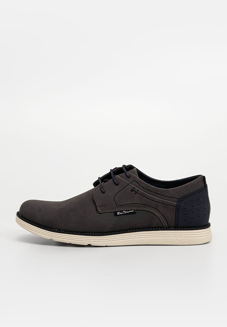 Dunkelgraue Leder-Schnürschuhe mit marineblauen Akzenten, durchbrochenen Details an der Ferse und einer hellen Gummisohle.