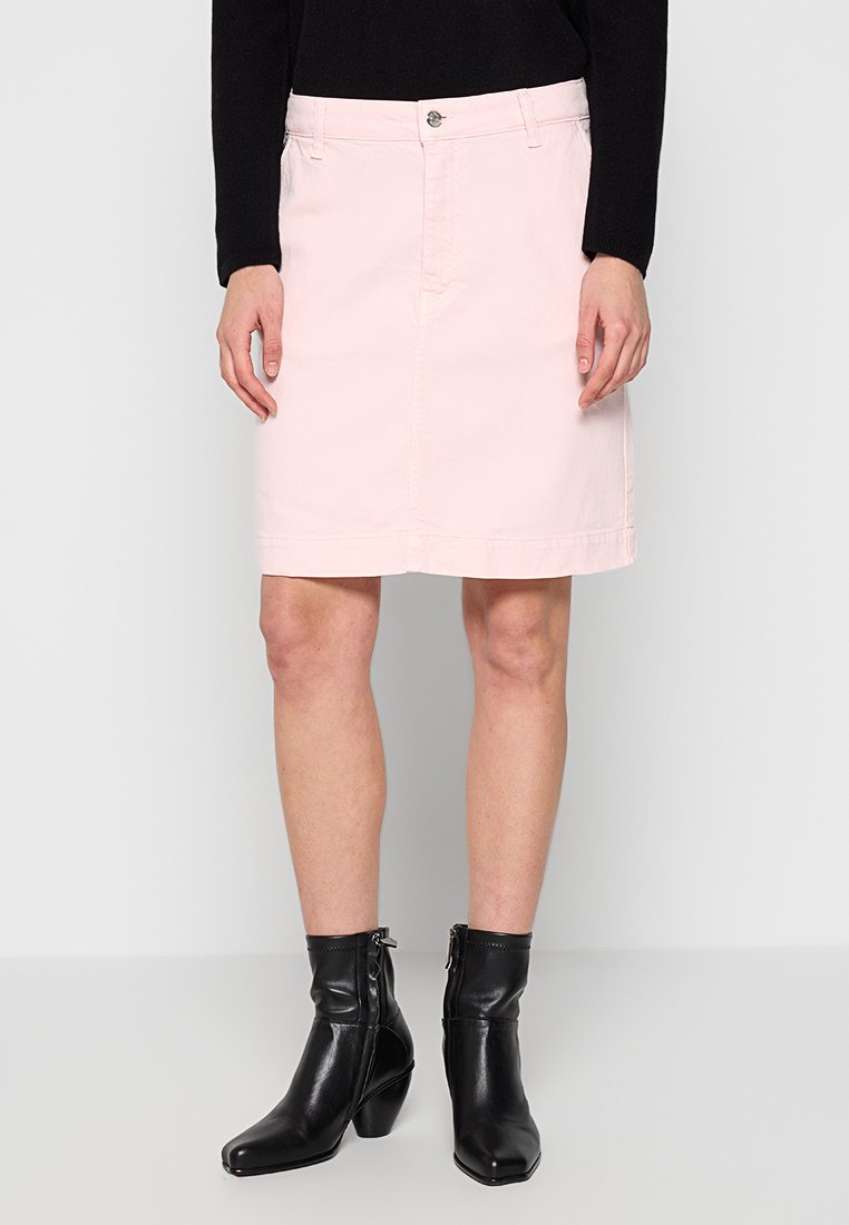 Hellrosa Jeansrock mit geradem Schnitt, Reißverschluss vorne und Knopfverschluss. Getragen mit schwarzen Knöchelstiefeln für einen schlankeren Look.