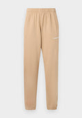 Beige Jogginghose mit elastischem Bund, schmal zulaufenden Beinen und seitlichen Taschen. Auf dem linken Oberschenkel befindet sich der kleine weiße Schriftzug "PEGADOR".