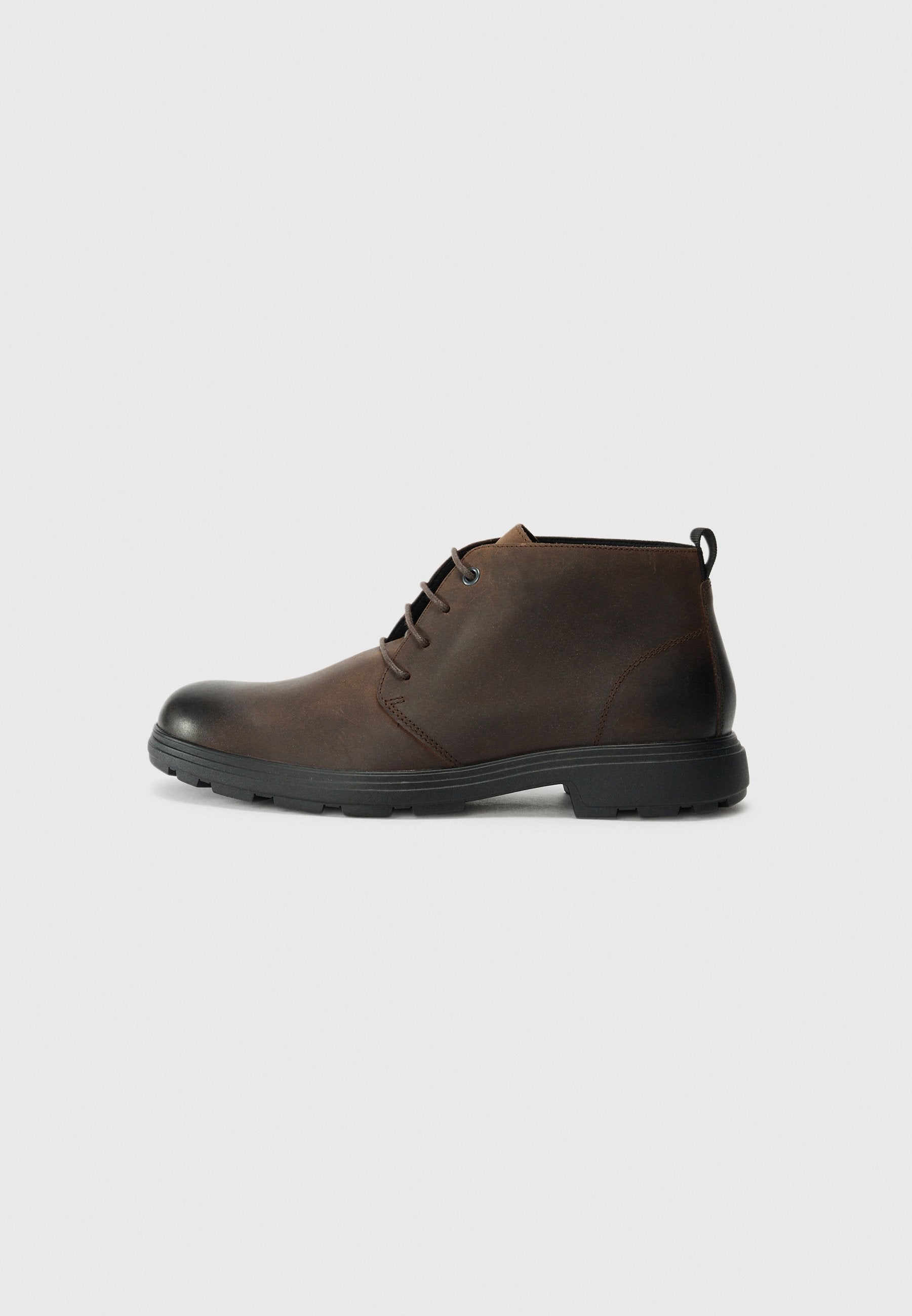 Braune Leder-Stiefeletten mit runder Zehenpartie, schwarzer Gummisohle und minimalistischem Schnürdesign. Strukturierte Oberfläche mit einer Schlaufe an der Ferse.