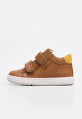 Brauner Leder- und Wildleder-Kindersneaker mit zwei Klettverschlüssen, weißer Sohle, gelber Fersenlasche und "GEOX"-Markierung an der Seite.