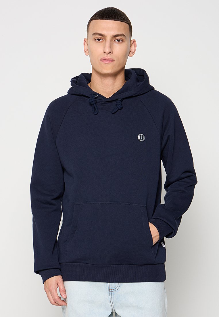 Marineblaue Kapuzenjacke mit Kordelzug, Kängurutasche und gerippten Bündchen. Verfügt über ein kleines rundes Logo auf der Brust.