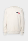 Hellbeige Sweatshirt mit langen Ärmeln, geripptem Rundhalsausschnitt und einem kleinen Logo in Marineblau und Rot auf der linken Brust. Weicher Stoff.