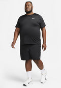 Schwarzes Nike Feuchtigkeitstransport-T-Shirt und Shorts. Weißes Nike-Logo auf dem Shirt und den Schuhen. Das Model trägt weiße Socken mit sportlichen Schuhen mit weißer Sohle.