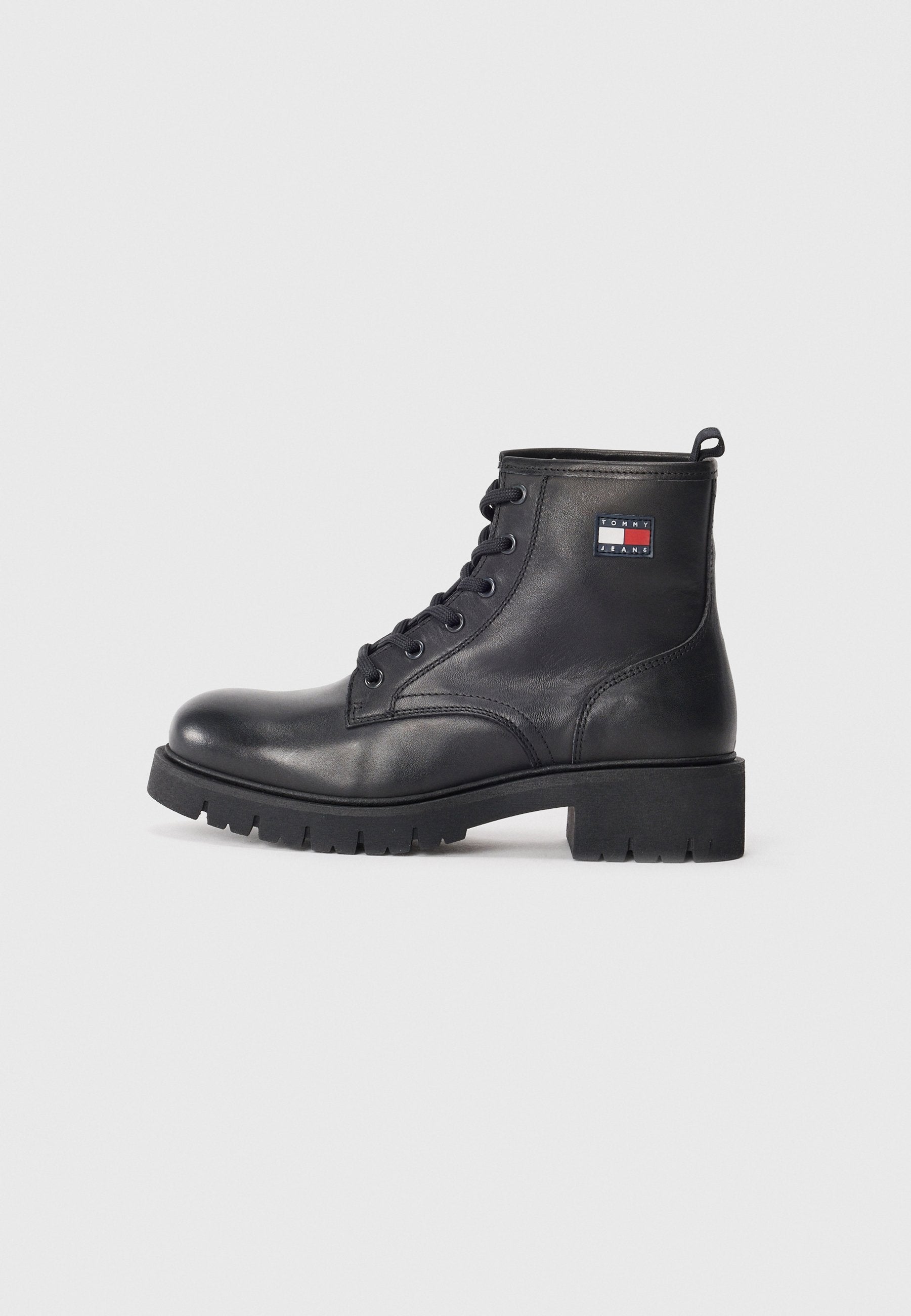 Schwarze Leder-Stiefel bis zum Knöchel mit runder Zehenpartie, Schnürverschluss auf der Vorderseite, robuster Gummisohle und einem Logopatch an der Seite. Glatte Textur, stabile Konstruktion.