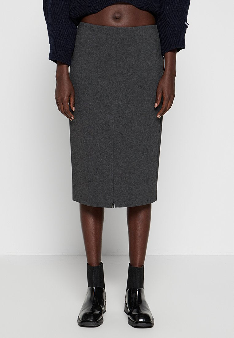 Grauer Bleistiftrock aus strukturiertem Stoff mit Schlitz hinten, kombiniert mit schwarzen Ankle Boots und einem lockeren, marineblauen Pullover.