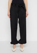 Schwarze, weit geschnittene Pants mit gebundenem Bund, ausgestattet mit zwei Fronttaschen und glatter Textur, kombiniert mit spitzen weißen Absatzschuhen.