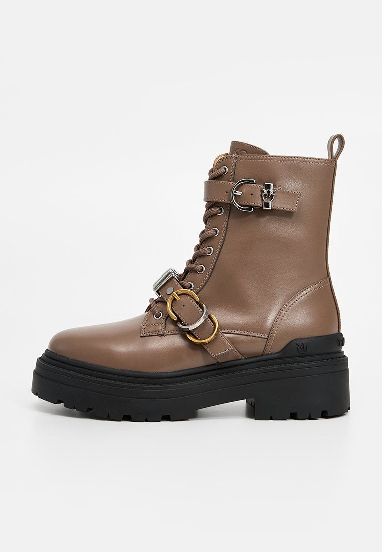 Brauner Lederstiefelette mit vorderer Schnürung, silbernen und goldenen Schnallendetails, dicker schwarzer Gummisohle und strukturierter Oberfläche.