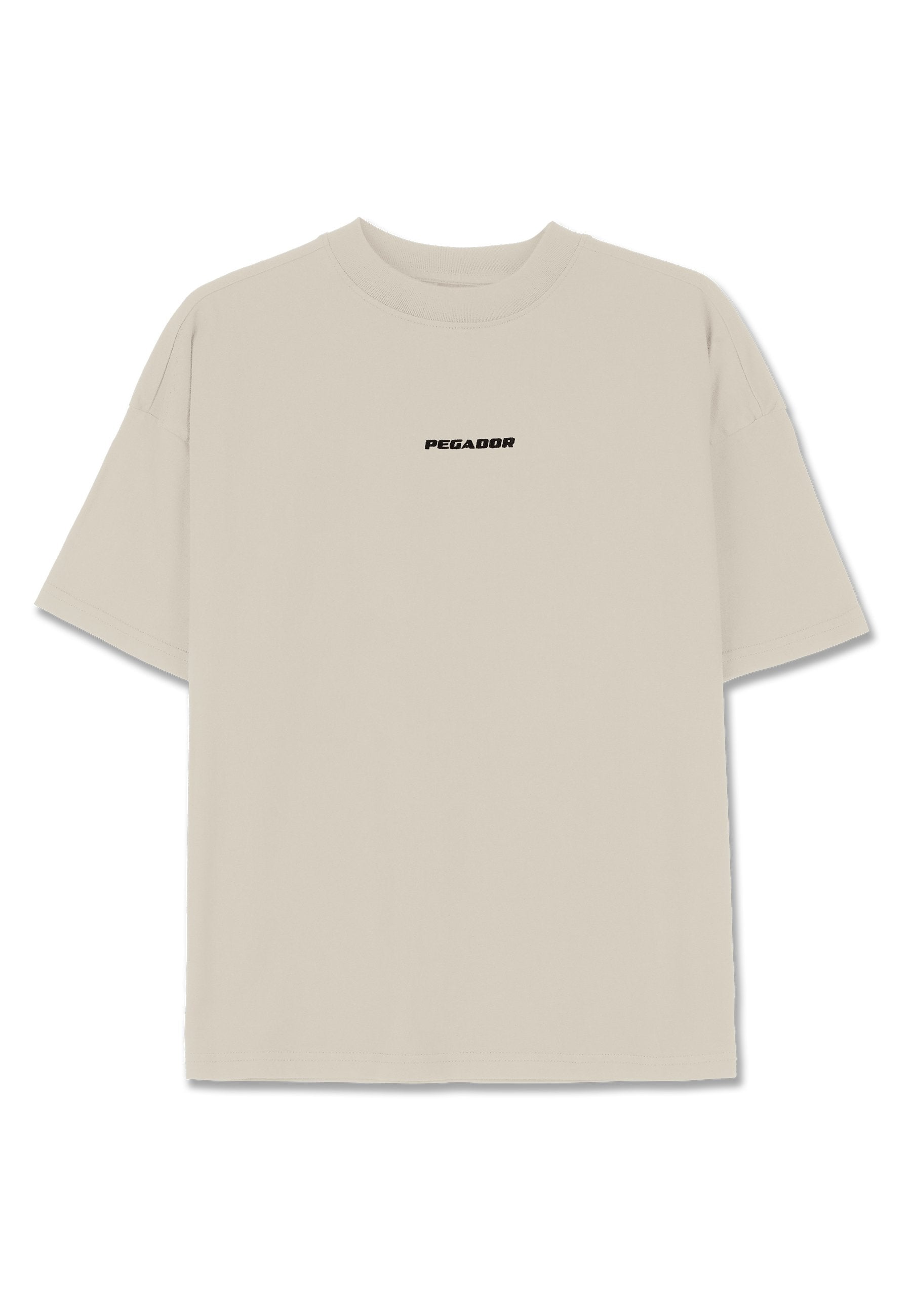Helles beiges Baumwoll-T-Shirt mit kurzen Ärmeln, lässiger Passform und einem schwarzen "PEGADOR"-Logo auf der Vorderseite. Glatte Textur, Rundhalsausschnitt.