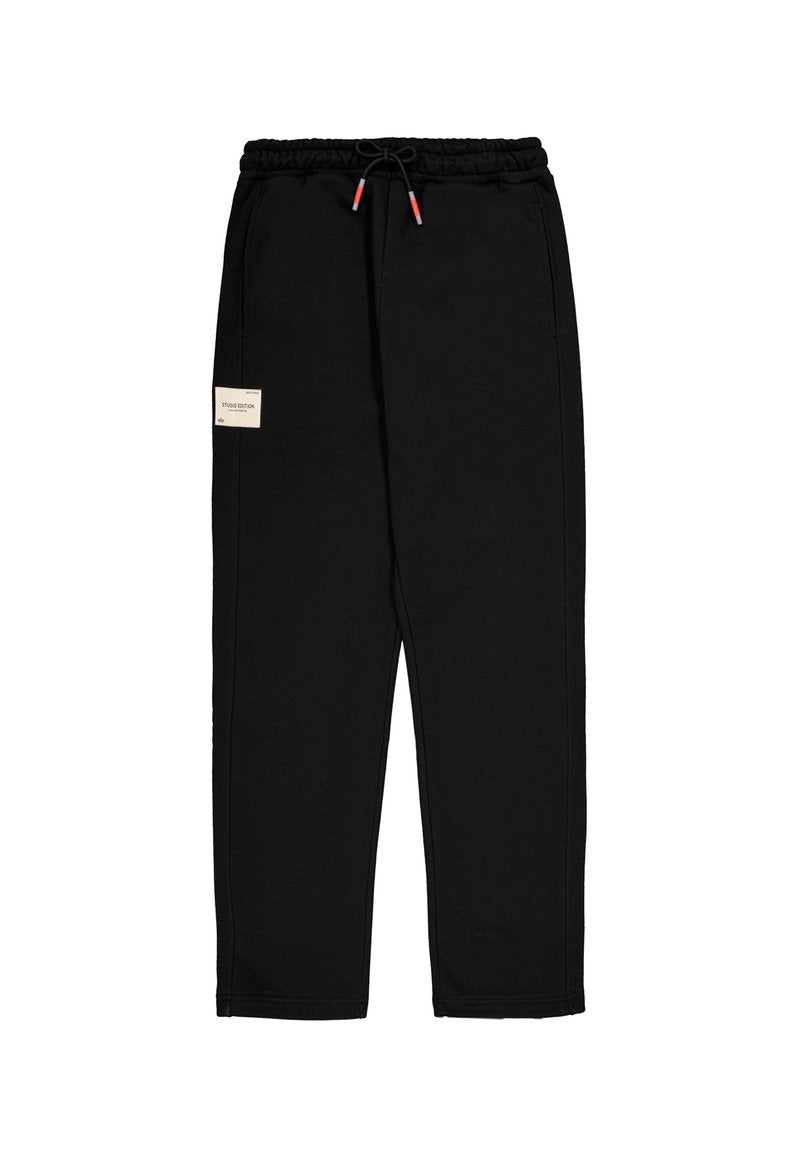 Schwarze Sweatpants mit elastischem Bund und verstellbarem Kordelzug mit roten Spitzen sowie einem kleinen beigen Aufnäher am linken Oberschenkel.