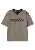 Kurzärmliges, lockeres T-Shirt aus taupefarbener Baumwolle mit braunem V-Ausschnitt und schwarzem "pegador"-Logo auf der Brust.