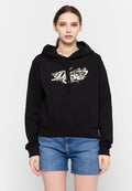 Schwarzer Kapuzenpullover mit einem grafischen Design auf der Vorderseite, das botanische Elemente zeigt. Kombiniert mit Denim-Shorts, die einen lässigen Stil präsentieren.