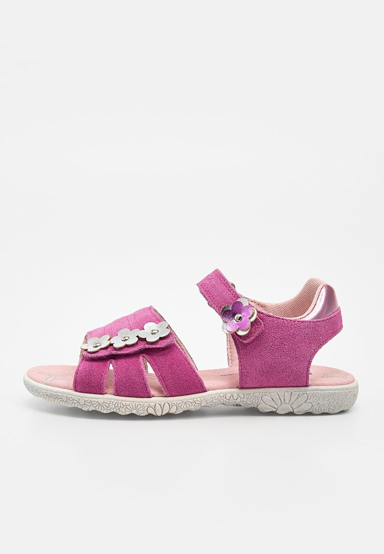 Rosa Kindersandale mit floralen Ausschnitten, silbernen und lila Blumenverzierungen sowie einem Klettverschluss am Knöchelriemen auf einer strukturierten weißen Sohle.