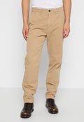 Beige Baumwollchinos mit geradem Bein, ausgestattet mit seitlichen Taschen und einem Knopfverschluss. Getragen mit dunkelbraunen Schnürstiefeln.