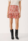 Mit einem floralen Muster in Rosa- und Rottönen, Rüschenschichten und einem fließenden Design. Kombiniert mit schwarzen Ankle Boots.