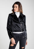 Schwarze Samt-Bikerjacke im cropped Stil mit einem geschlitzten Revers, Reißverschluss und zwei seitlichen Taschen. Getragen über einem weißen Rollkragenpullover.