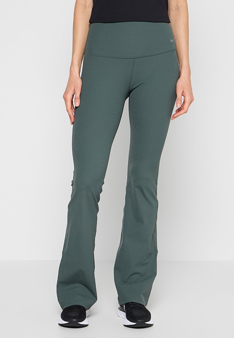 Grüne gerippte Yogahosen mit weitem Schnitt und hohem Bund, kombiniert mit schwarzen Sneakers. Weicher Stoff, minimales Branding-Detail.