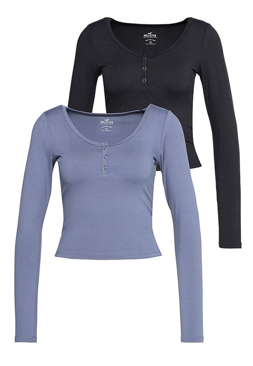 Zwei Langarm-Henley-Shirts, eines schwarz und eines in gedecktem Blau, mit Rundhalsausschnitten und drei Knöpfen an der Vorderseite.