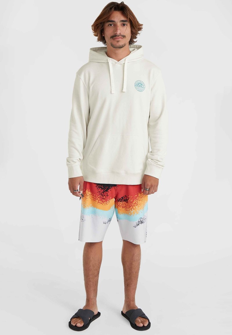 Cremefarbener Kapuzenpullover mit Fronttasche und türkisfarbenem Logo; leuchtend multicolor Badehose mit Farbverlaufsmuster; schwarze Flip-Flops.