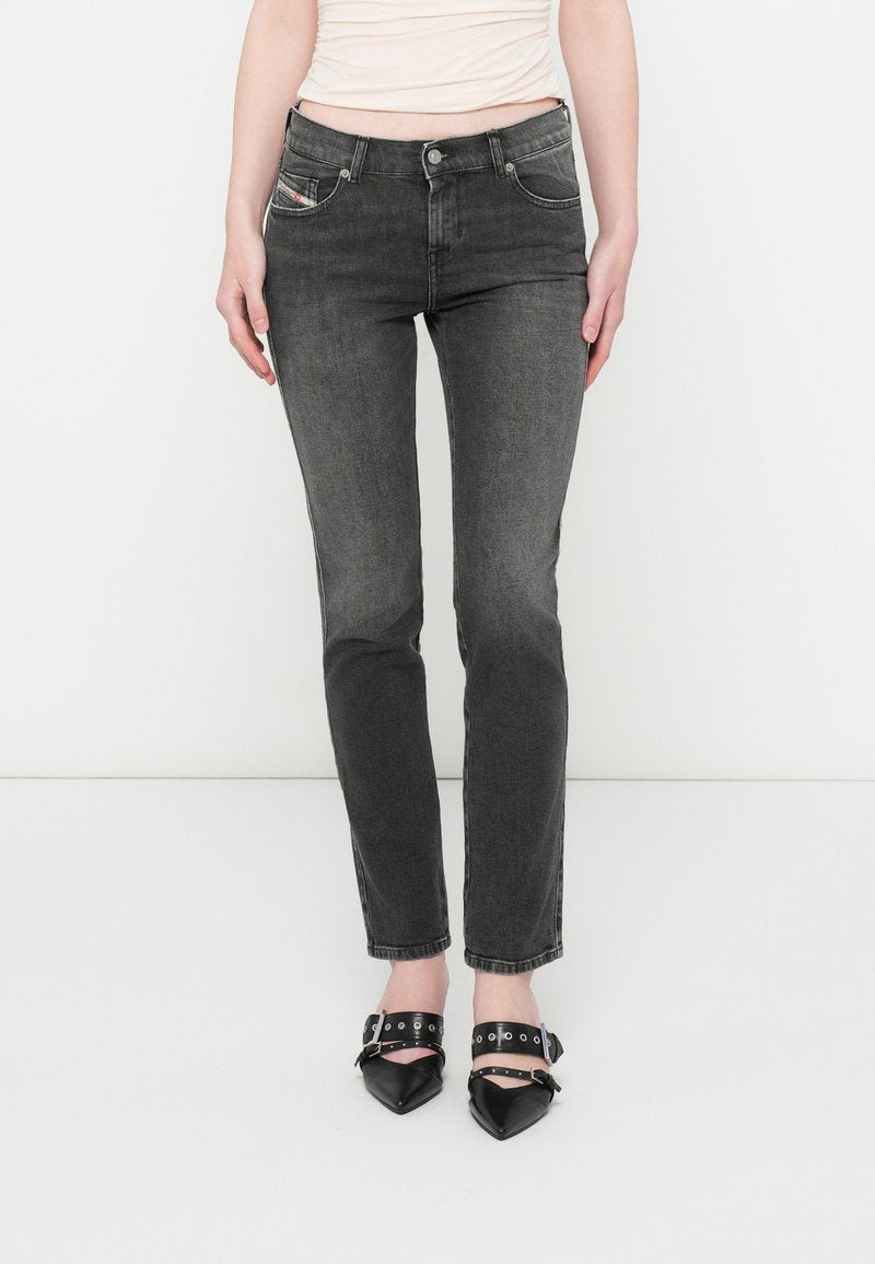 Schlanke schwarze Jeans mit einem verblassten Look, ausgestattet mit fünf Taschen und silberner Naht. Kombiniert mit schwarzen spitzen High Heels mit Riemen-Details.