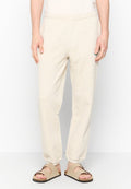 Beige Baumwoll-Sweatpants mit einem elastischen Bund, schmal zulaufenden Beinen und einer weichen Textur. Getragen mit beigen Sandalen, die einen lässigen Look präsentieren.