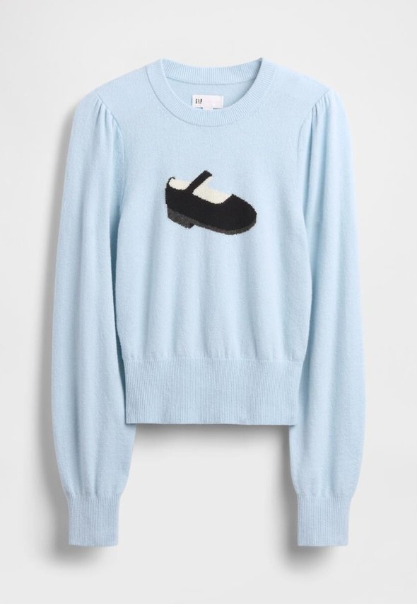 Hellblauer Pullover mit einem schwarz-weißen, aufgestickten Schuhmotiv auf der Vorderseite, langen Ärmeln sowie einem gerippten Saum und Bündchen.