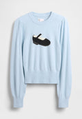 Hellblauer Pullover mit einem schwarz-weißen, aufgestickten Schuhmotiv auf der Vorderseite, langen Ärmeln sowie einem gerippten Saum und Bündchen.