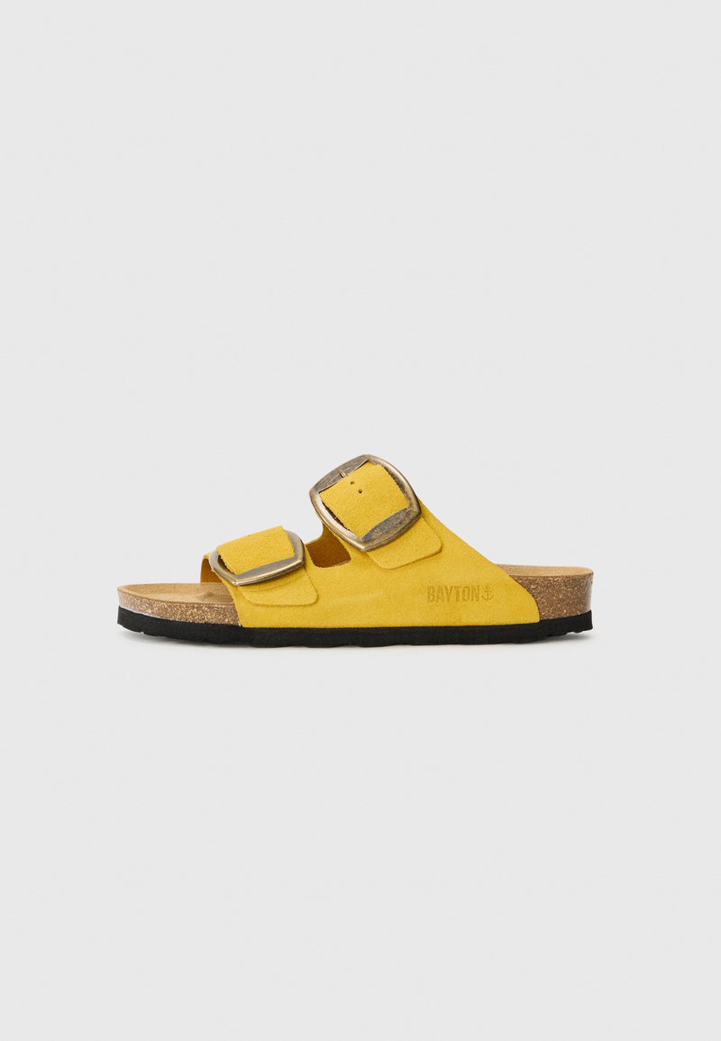 Gelbe Wildleder-Sandale mit zwei verstellbaren Riemen, Korkfußbett und schwarzer Gummisohle. Mit strukturierter Oberfläche und dezentem Branding ausgestattet.