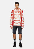 Rote und weiße Kapuzenjacke mit großem "DIESEL"-Aufdruck, Kängurutasche und verstellbarem Kapuzenzug. Kombiniert mit grauen Shorts und schwarzen Mesh-Sneakern.
