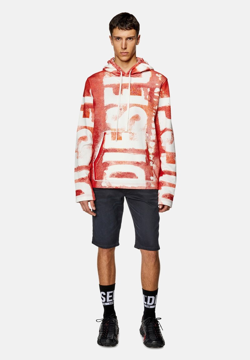 Rote und weiße Kapuzenjacke mit großem "DIESEL"-Aufdruck, Kängurutasche und verstellbarem Kapuzenzug. Kombiniert mit grauen Shorts und schwarzen Mesh-Sneakern.