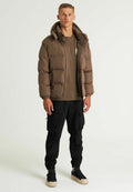 Braune Daunenjacke mit Kapuze, mit Reißverschluss vorne, elastischen Bündchen und Taschen, kombiniert mit einem braunen Shirt und schwarzen Cargo-Hosen.