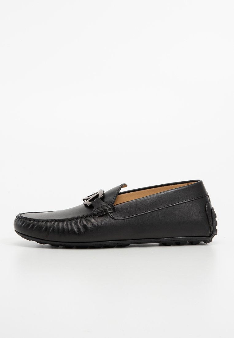 Schwarze Lederloafer mit runder Zehenform, strukturierten Akzenten und einer metallischen Schnalle, ausgestattet mit einer flexiblen Sohle und einem glatten Innenfutter.