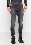 Schlanke, dunkelgraue Denim-Jeans mit subtilen Ausbleichungen, Fünf-Taschen-Design und Kontrastnähten, kombiniert mit schwarzen Sportschuhen.